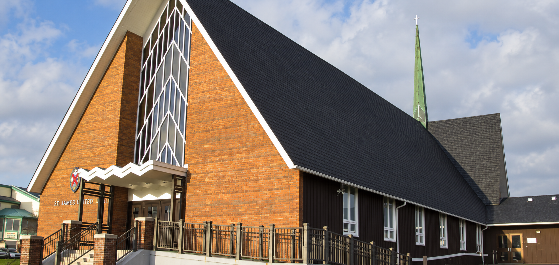 St. James United Church, with its distinctive steep roof, warm brick entrance and green spire.